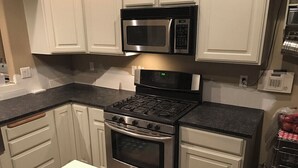 A kitchen with white cabinets, a stainless steel stove, and a microwave. - 2 king 2 twin beds 3Bed 2.5 Ba cozy Mer Home near Village with Hot tub (Meridian)