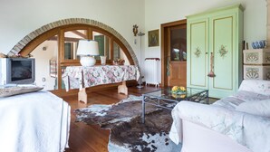 Une pièce chaleureuse avec un plafond en bois, une armoire verte, une table basse en verre et un tapis en peau de vache.