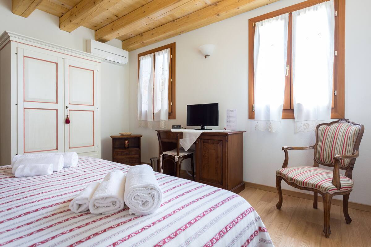 Ein Schlafzimmer mit einem Bett, einem Schreibtisch, einem Stuhl und einem Fernseher.