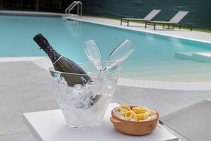 Poolmiljø med champagneflaske, is og glas i spand, samt en skål med chips.