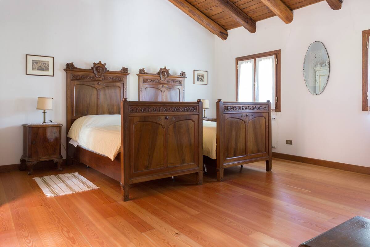 Ein Schlafzimmer mit einem hölzernen Bett, einem Nachttisch und einem Spiegel an der Wand.