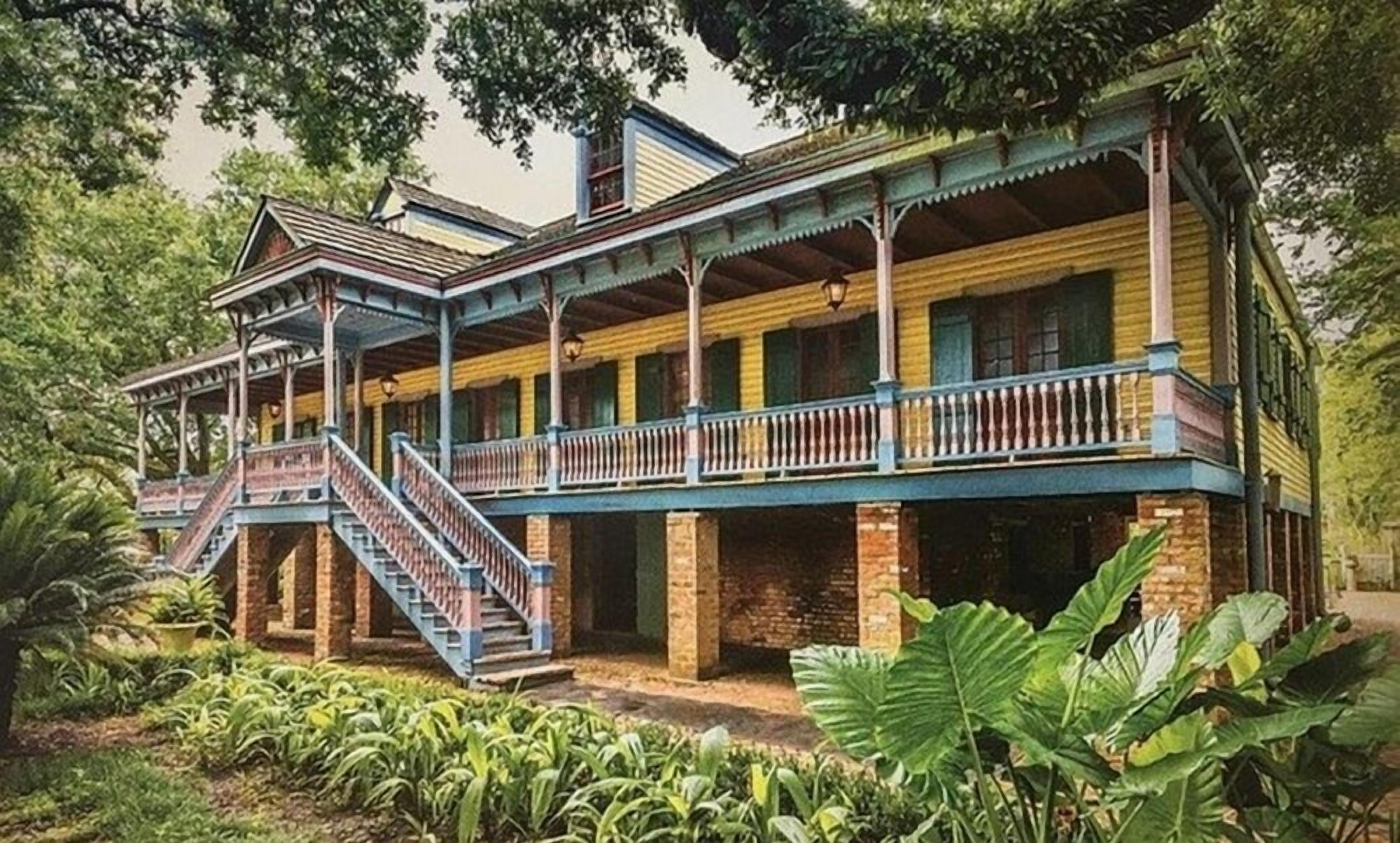Un edificio de estilo colonial de dos pisos con un balcón y una escalera que conduce al nivel superior.