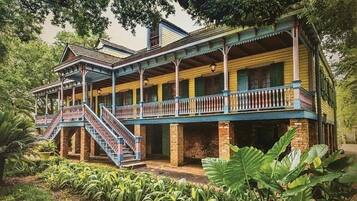 Un edificio de estilo colonial de dos pisos con un balcón y una escalera que conduce al nivel superior.