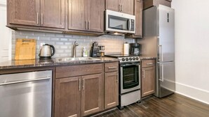 A kitchen with wooden cabinets, stainless steel appliances, a microwave, a refrigerator, and a stove.