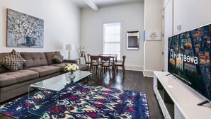 A modern living room with a sofa, coffee table, and a TV displaying 'Hosteva'.