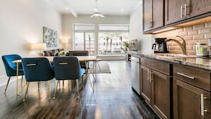 Una cocina moderna con armarios de madera oscura, encimera de mármol y zona de comedor con sillas azules y una mesa.