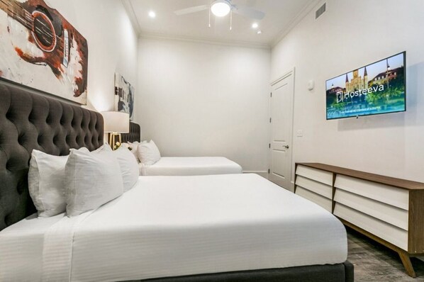 Une chambre d’hôtel avec deux lits, une télévision et une œuvre d’art accrochée au mur.