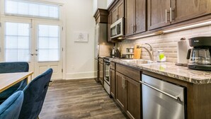 A kitchen with wooden cabinets, stainless steel appliances, and a marble countertop.