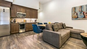 Eine moderne Küche mit Holzausstattung, Edelstahlgeräten und einer Essecke mit blauen Stühlen und einem grauen Sofa.