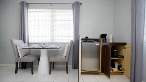 Una cocina moderna con una mesa de comedor, sillas, un refrigerador empotrado y un mueble de madera con utensilios de cocina.