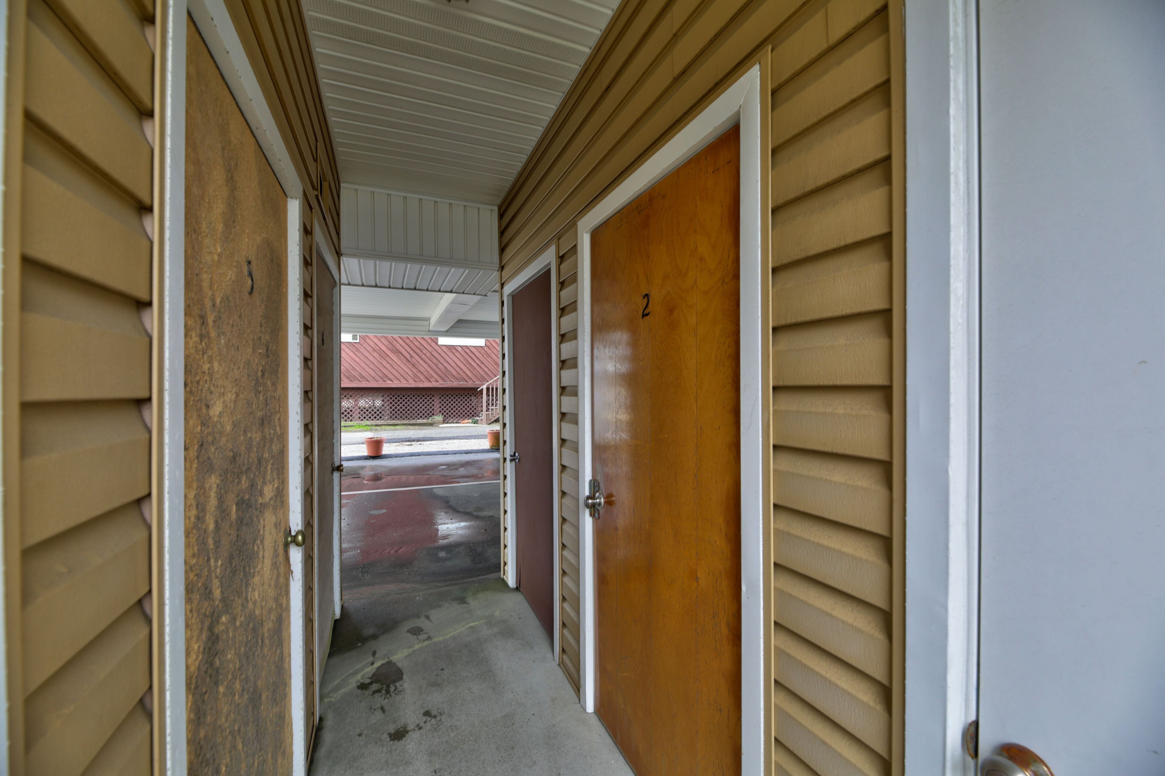A narrow hallway with wooden doors and a concrete floor.