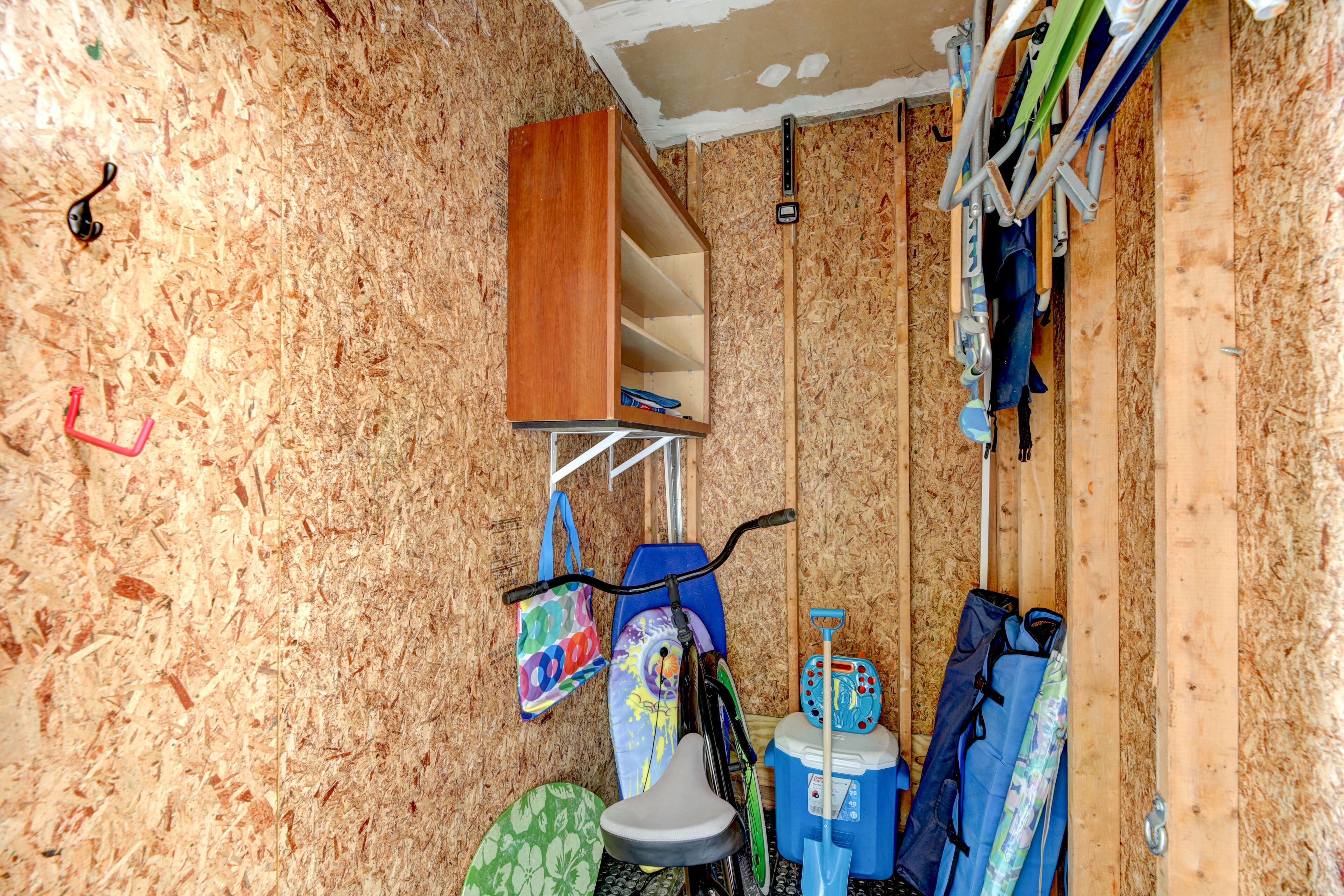 Una habitación con pared de madera, una bicicleta, una mesita con un paraguas azul y un bolso colorido.