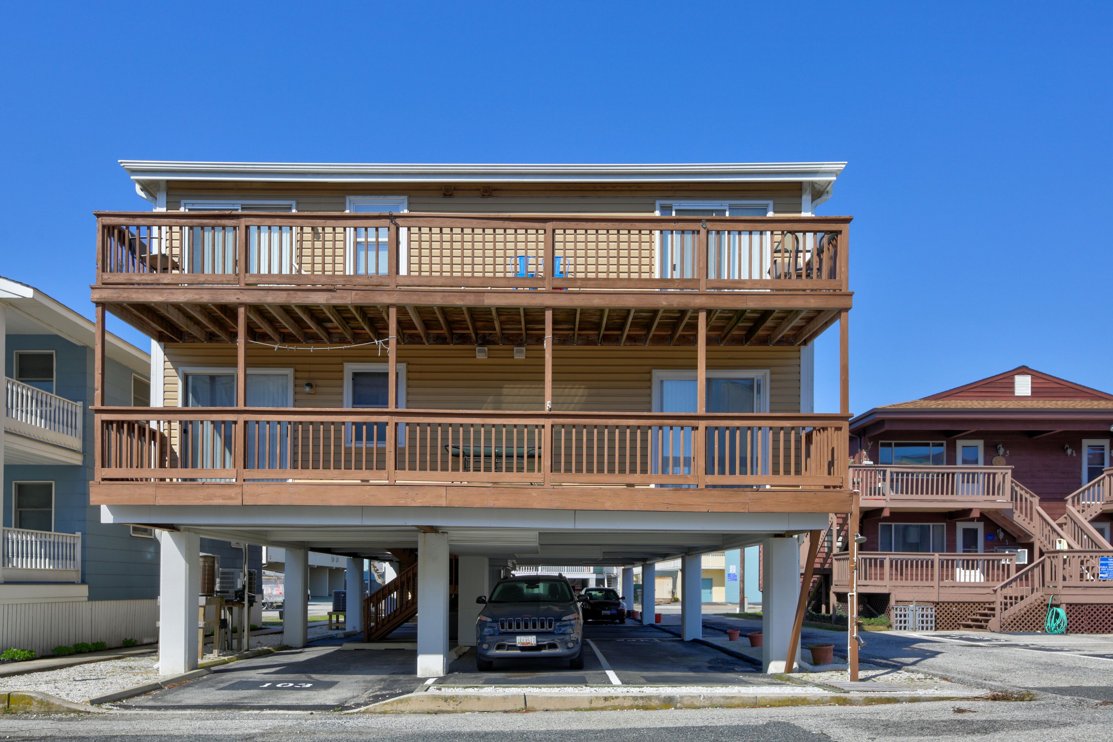 A multi-story building with a covered parking area and a staircase leading to the upper floors.