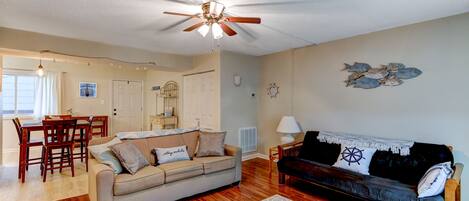 A living room with a ceiling fan, a sofa, a couch, a dining table with chairs, and a patterned rug.