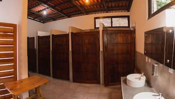 A bathroom with wooden stalls, a wooden bench, and two sinks.