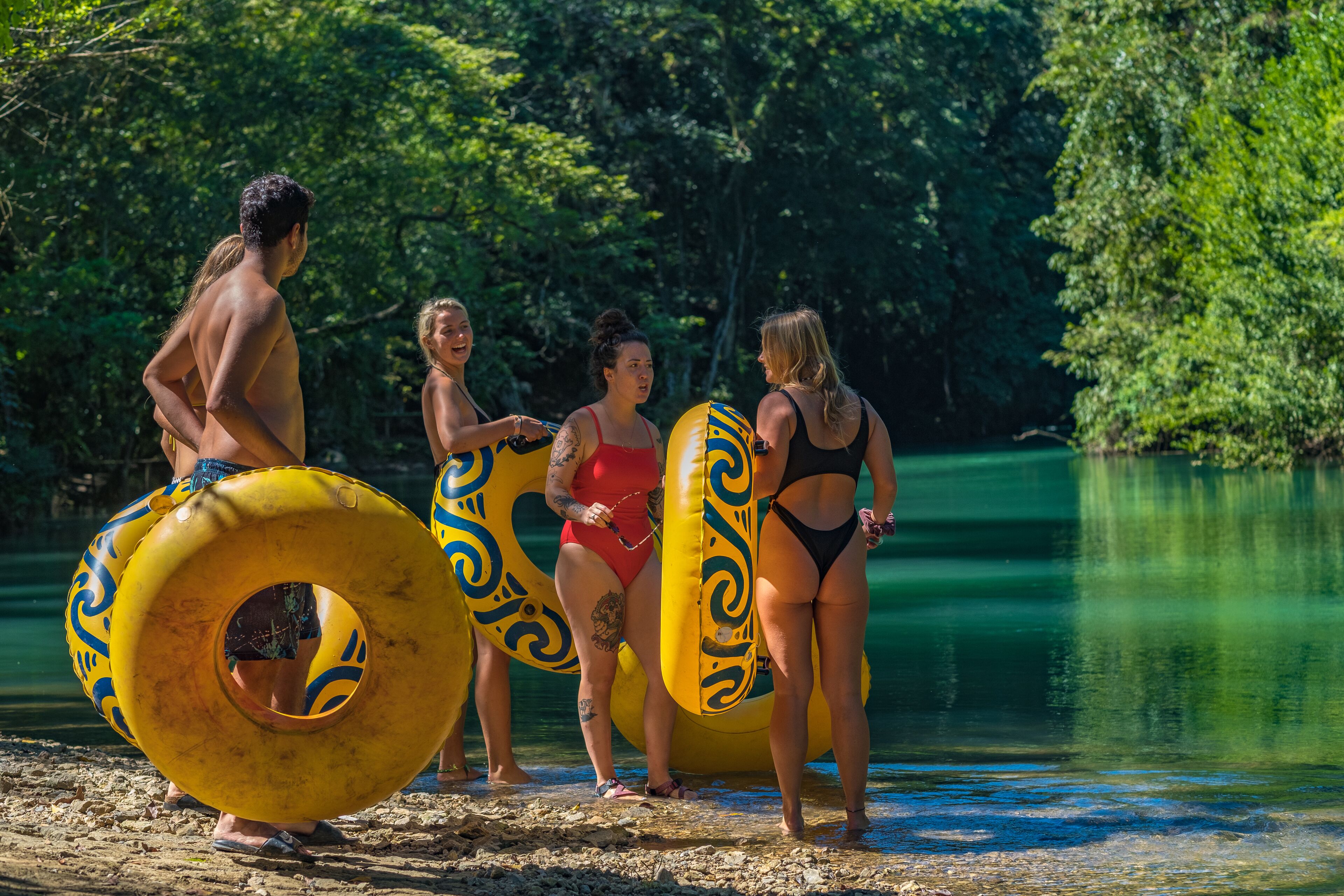 Un grupo de personas junto a un lago, con flotadores hinchables.