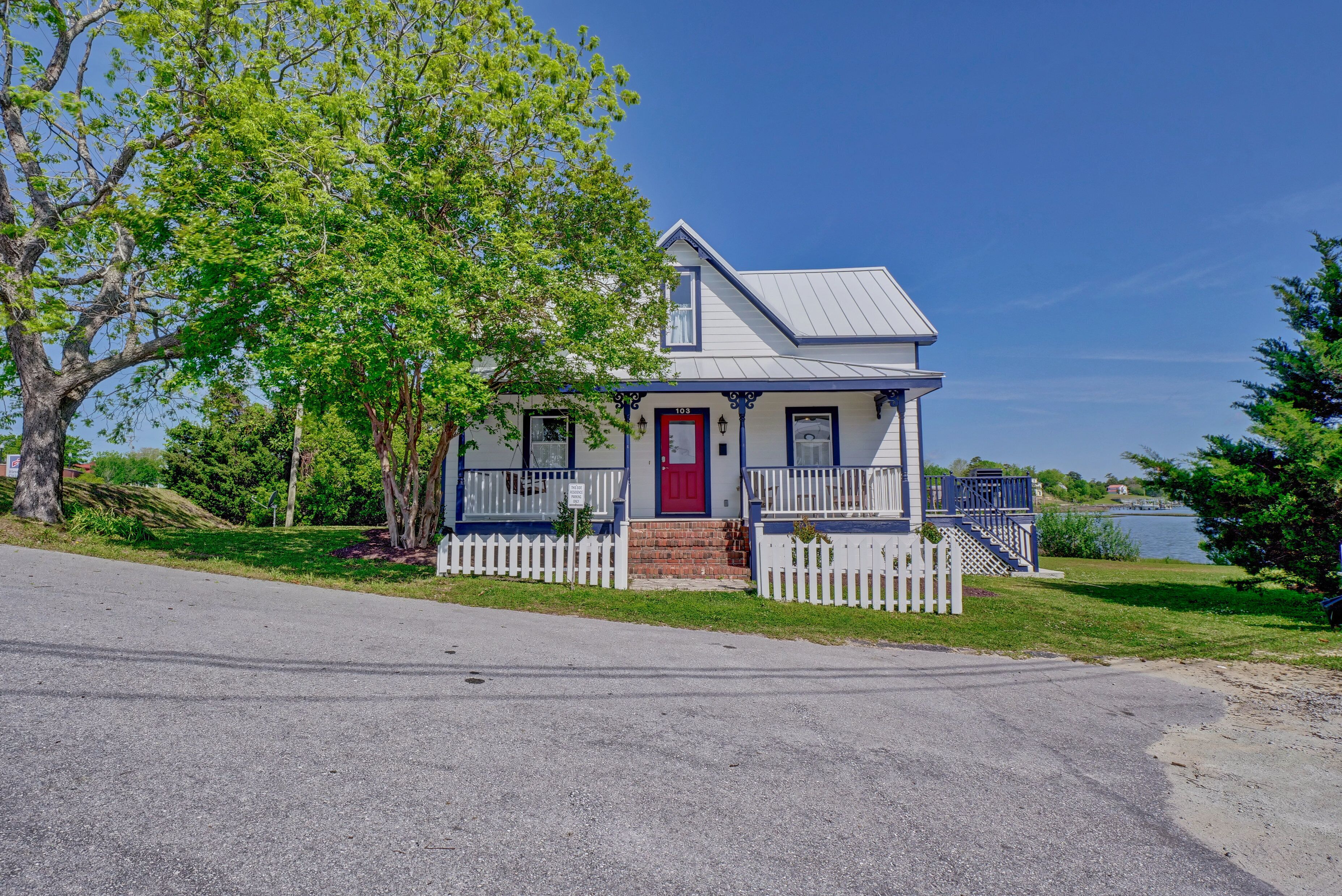 A two-story house with a red door, white picket fence, and a small porch.
