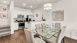A modern kitchen with stainless steel appliances, a dining area with a glass table and chairs, and a chandelier. - 3 BD/ 2 BA/ Lucaya Village (18-102) (Kissimmee)
