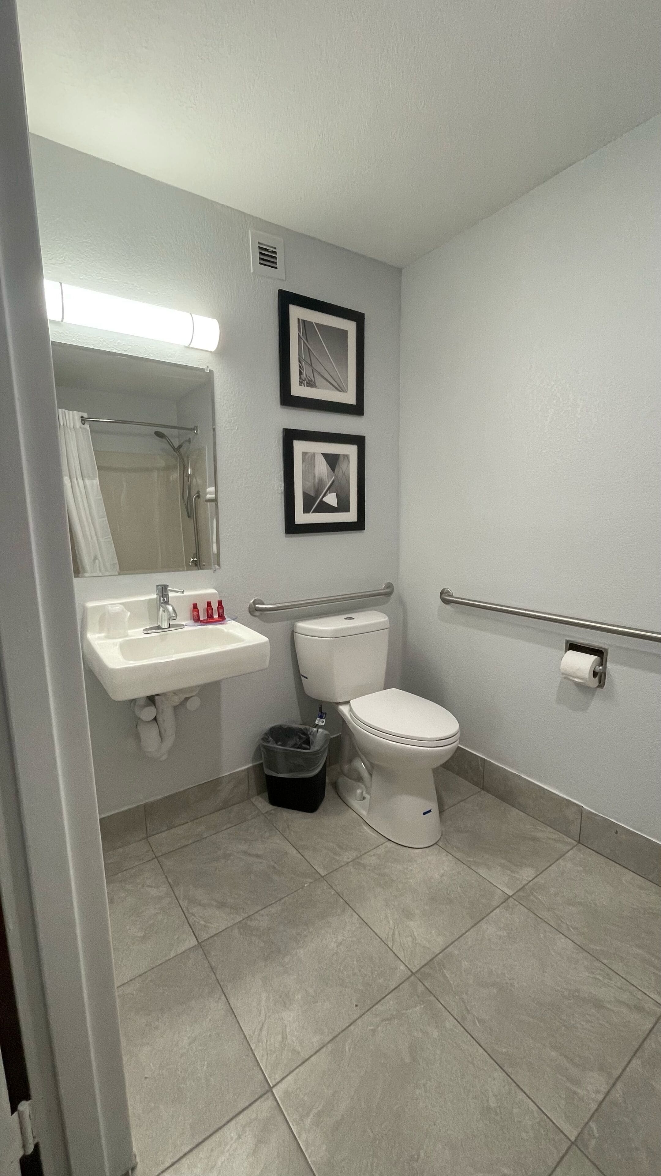 A bathroom with a sink, toilet, and a shower area. There are two framed pictures on the wall.