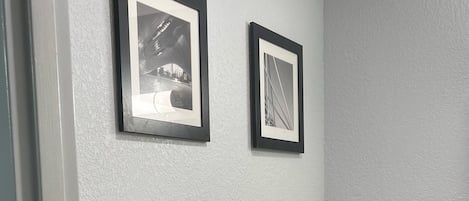 A bathroom with a toilet, a towel rack with folded towels, and two framed pictures on the wall.