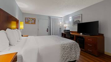 Hotelkamer met een groot bed, een bureau met een computer, een televisie en een raam met gordijnen.