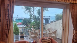 A room with two chairs, a small table, and a pool table. The room has a view of a garden and a building outside. - The Sands Hotel (Paignton)