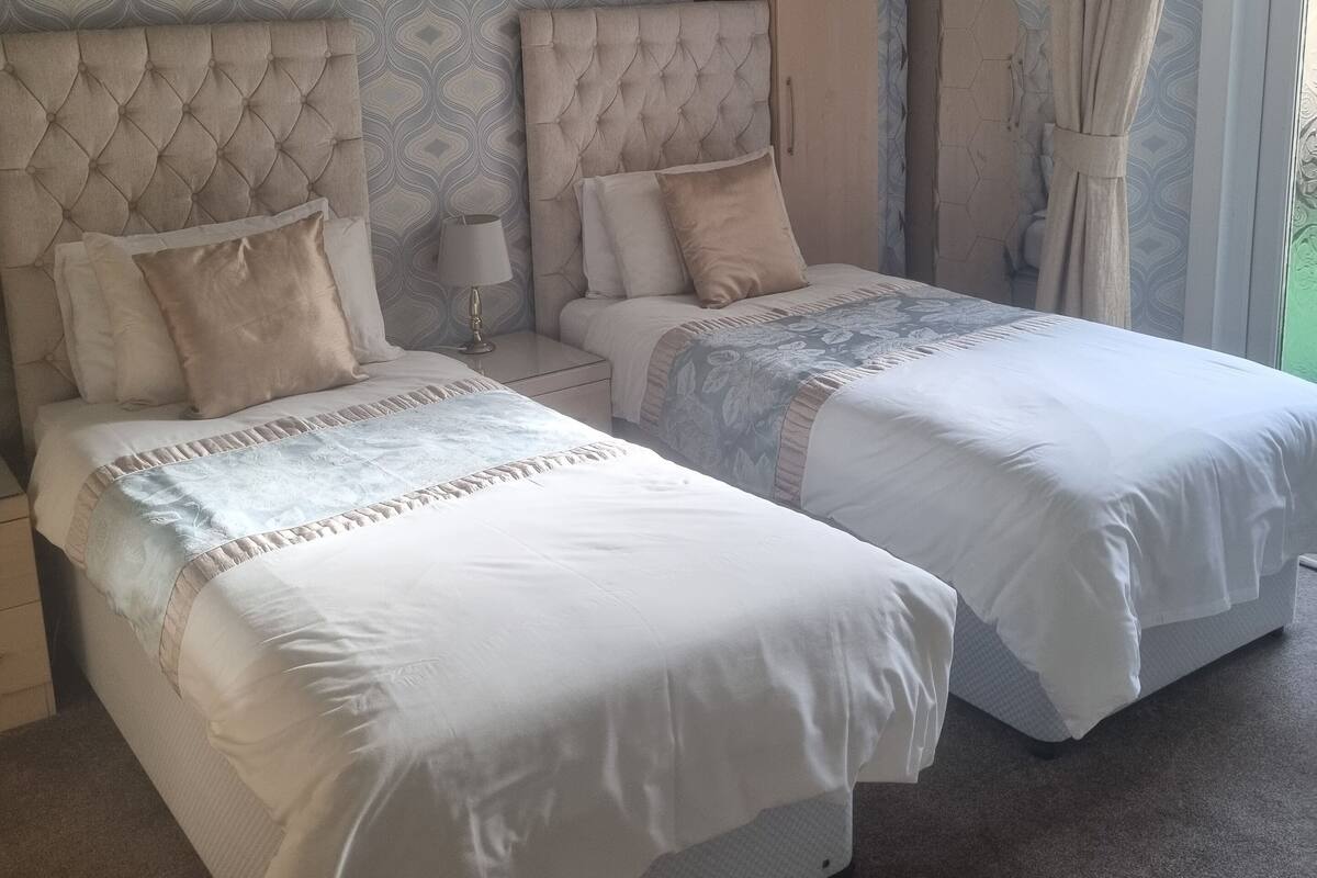 A double bed room with a tufted headboard, a nightstand, and a wardrobe.