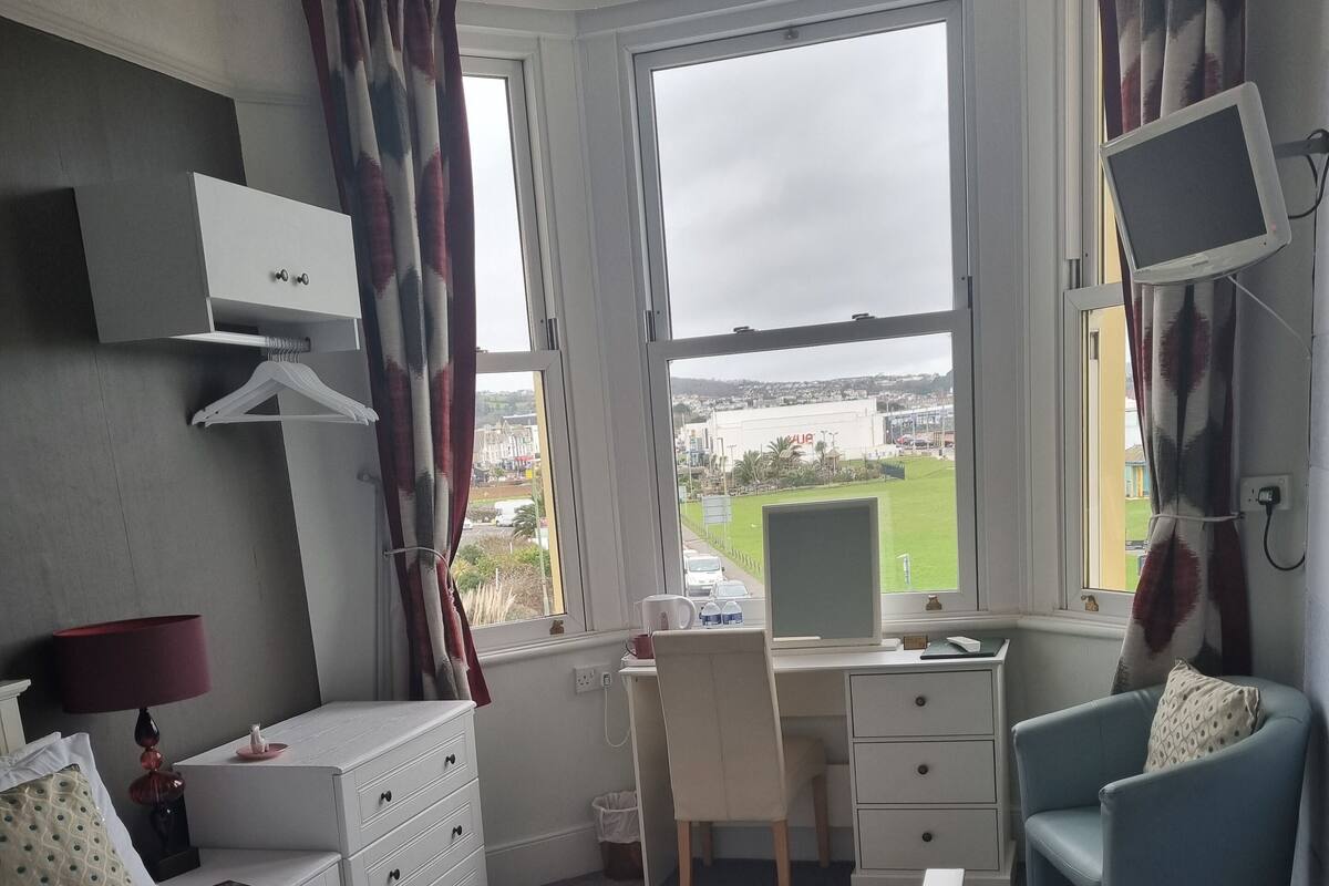 A hotel room with a bed, a desk with a computer, a chair, and a TV.