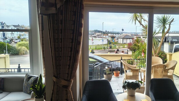 A balcony with wicker furniture, a view of the street, and a potted plant. - The Sands Hotel (Paignton)