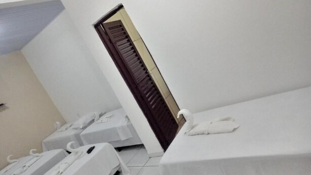 A hotel room with two beds, a wooden door, and a white wall.