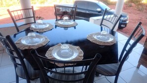A round table with six chairs, each with a woven placemat and a clear glass cover.