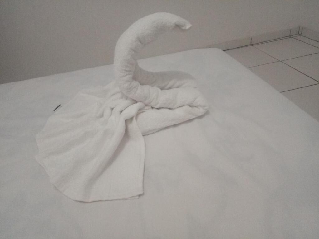 A neatly folded white towel on a bed in a hotel room.
