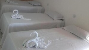 A hotel room with two single beds, each with a neatly folded towel and pillow.