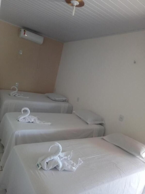 Ein Hotelzimmer mit zwei Einzelbetten, jeweils mit ordentlich gefaltetem Handtuch und Kissen.