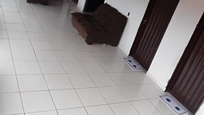 A spacious room with white tiled flooring, two brown sofas, and a door.