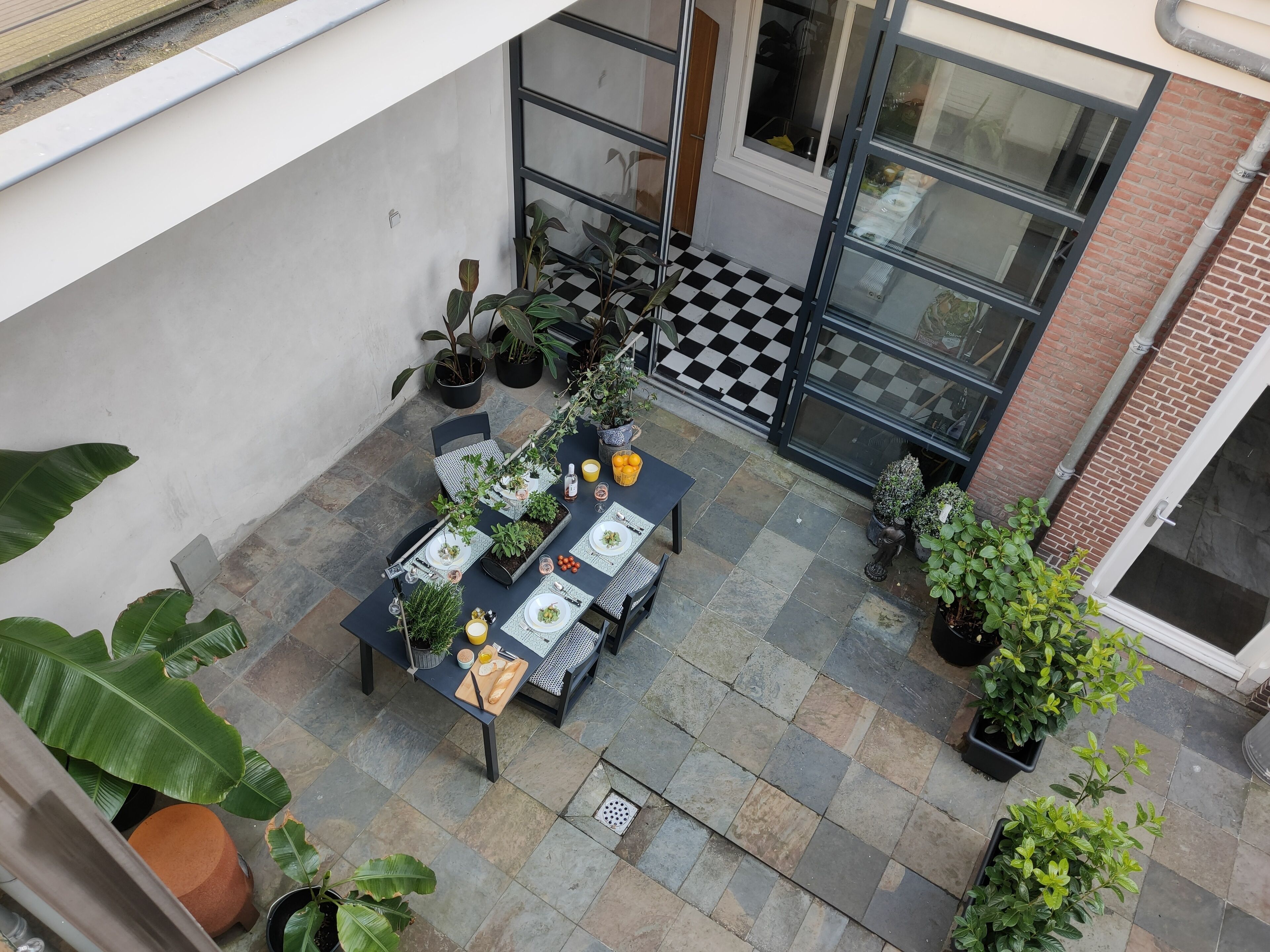 Un espace patio doté d’un sol à carreaux, de sièges extérieurs et de plantes en pot.