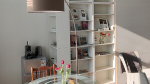 A modern room with a glass table, a metal lamp, a white bookshelf, and a wooden chair. - B&B Hart van Leiden (Leiden)