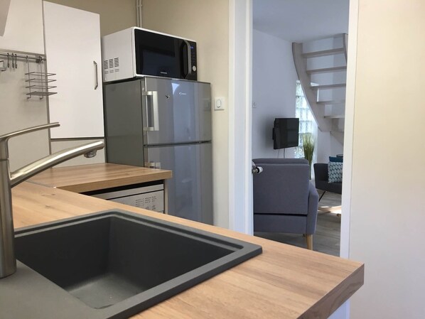 A modern kitchen with a stainless steel refrigerator, a microwave, and a sink.