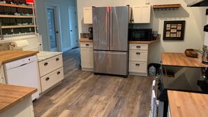 A modern kitchen with a stainless steel refrigerator, wooden countertops, and a dishwasher. - Country Getaway near Seattle (Maple Valley)