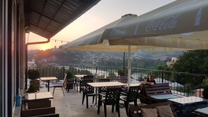 A terrace with outdoor seating, umbrellas, and a view of a river and town. - Green flower is located in the historical part of Kutaisi.5-minute walk  centre. (Kutaisi)