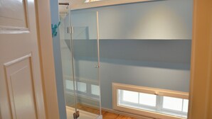 Een kamer met een douchecabine van glas, een dakraam en een raam.