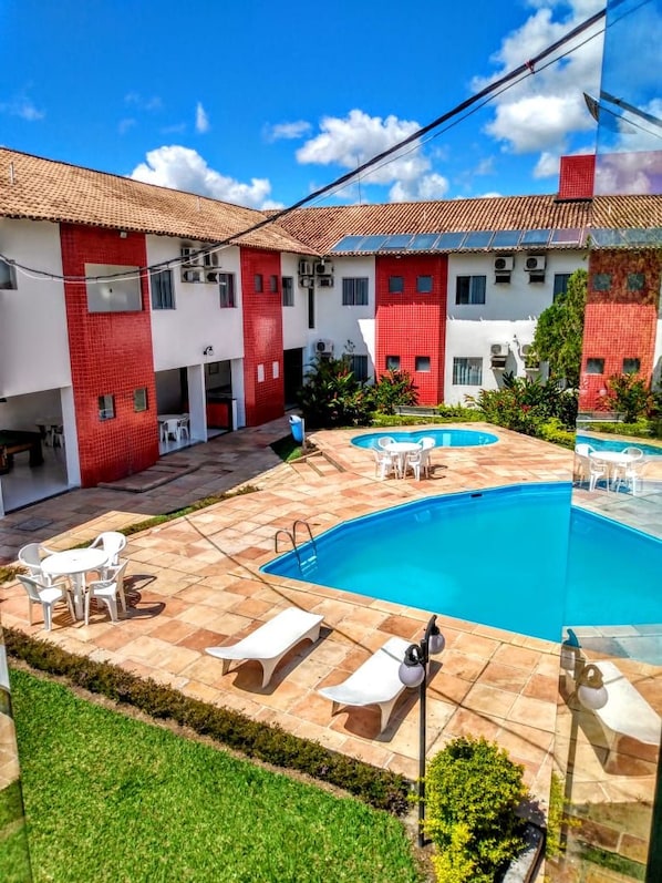 A courtyard with a swimming pool, outdoor seating, and a building with red and white walls.
