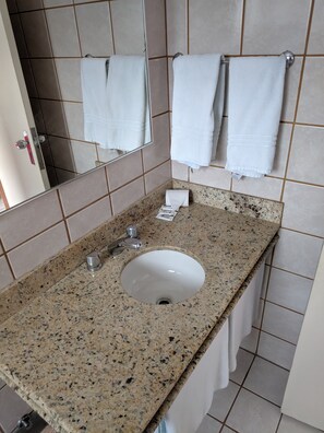 A bathroom with a granite countertop sink, a mirror, and two white towels hanging on the wall.