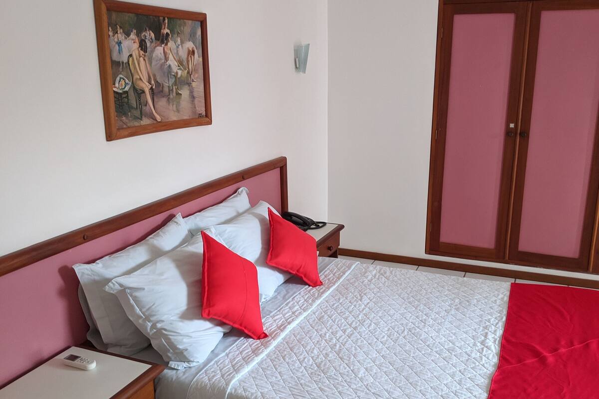 A bedroom with a bed, nightstand, and a painting on the wall.