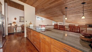 Une cuisine spacieuse avec des meubles en bois, un grand îlot central et des luminaires suspendus.