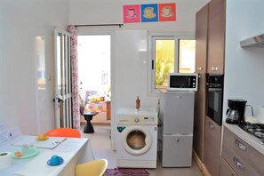 A compact kitchen with a washing machine, microwave, and stove.