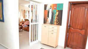 Um corredor com uma porta de madeira, um armário bege e um quadro na parede.