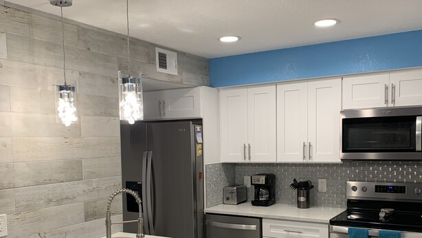 A modern kitchen with a central island, stainless steel appliances, and a blue accent wall.