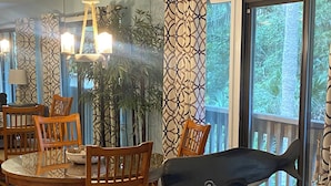 A dining area with a glass table, wooden chairs, and a chandelier. - Beachwalk 106 Shipyard Hilton Head Island, 5 Min. Walk to Beach (Hilton Head Island)