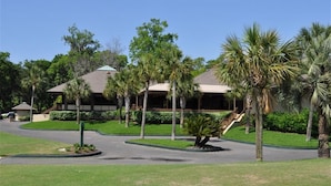 A building with a covered walkway, surrounded by palm trees and greenery. - Beachwalk 106 Shipyard Hilton Head Island, 5 Min. Walk to Beach (Hilton Head Island)